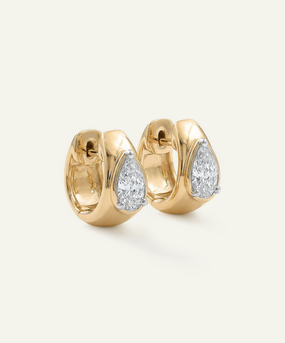Gold hoop earrings with diamond accents on a light beige background