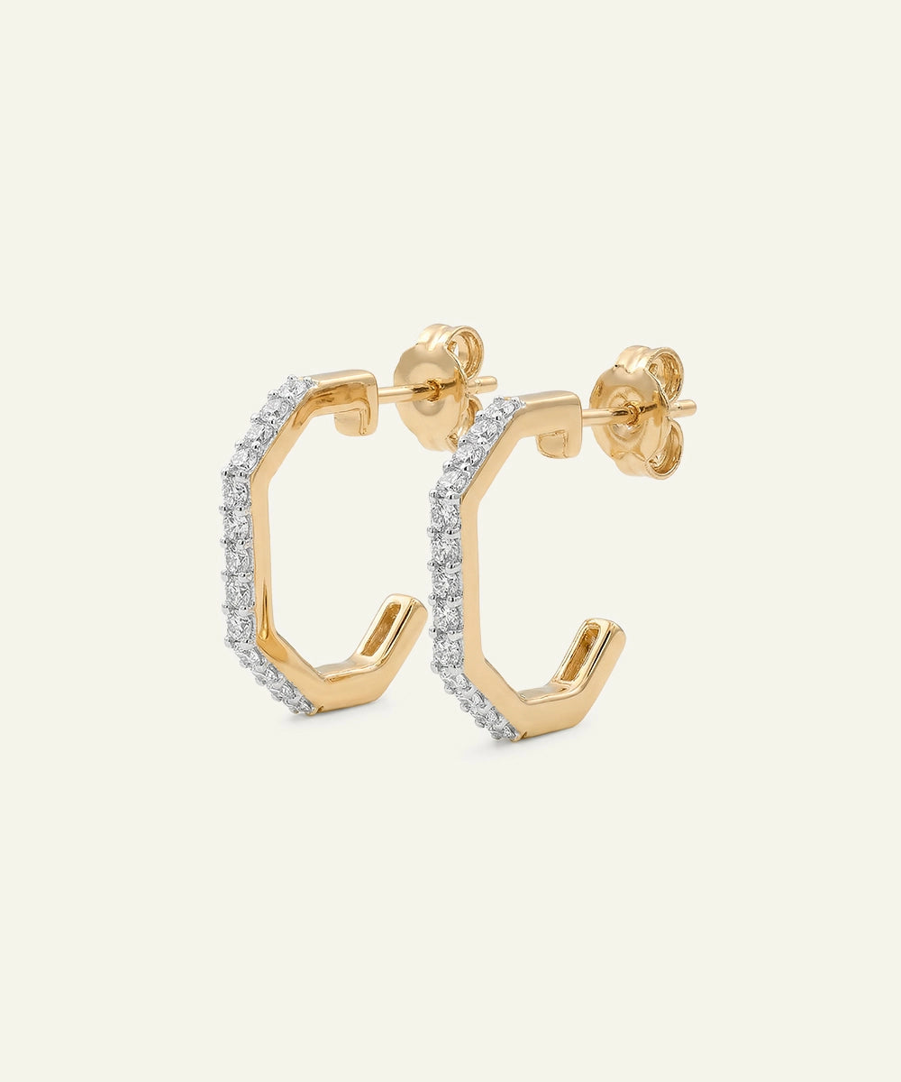 Gold hoop earrings with diamond accents on a light beige background