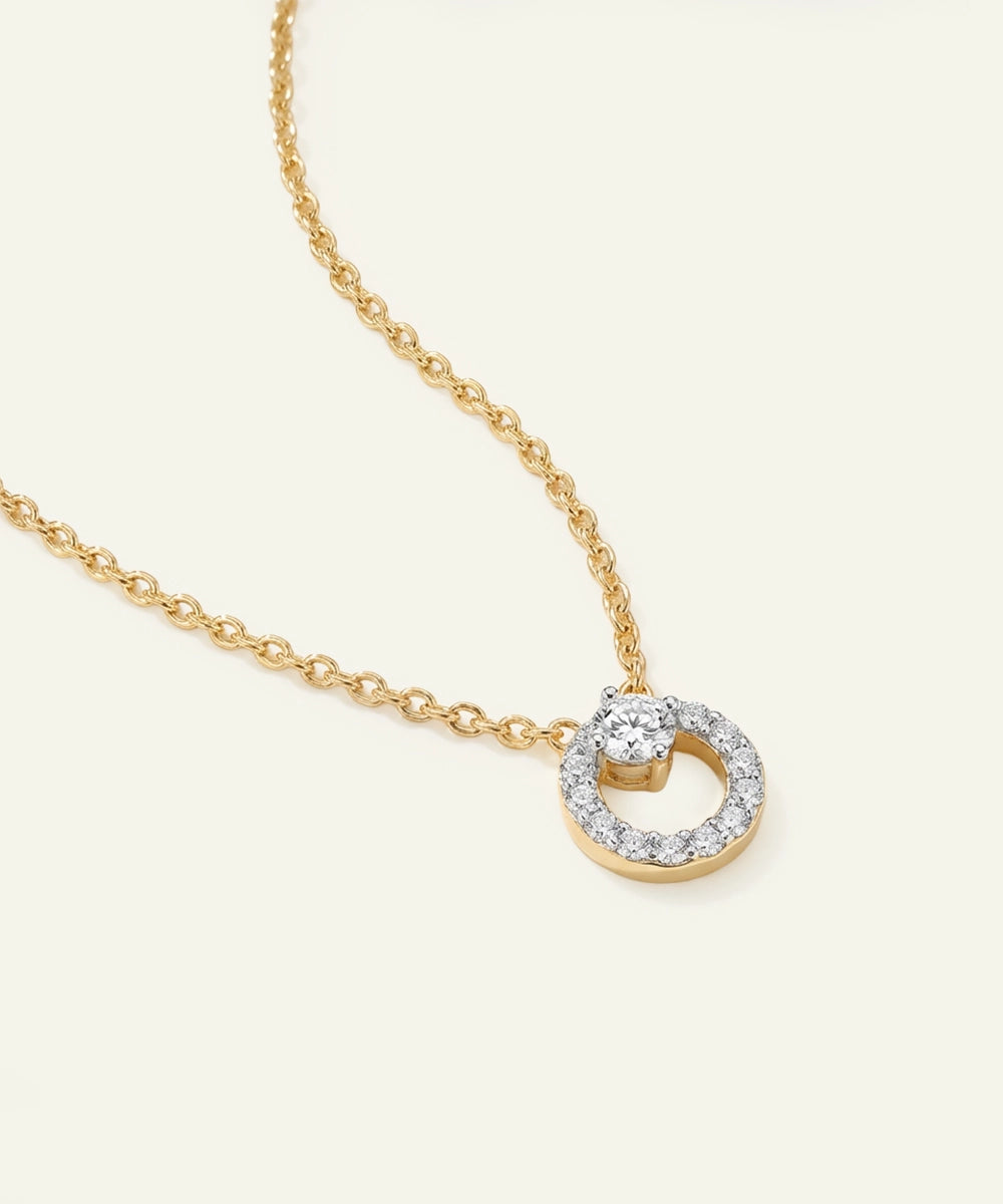Gold necklace with a diamond pendant on a light beige background