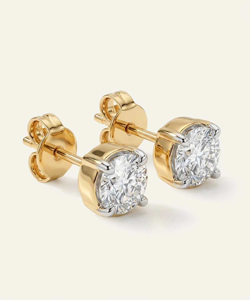 Gold diamond earrings on a light beige background