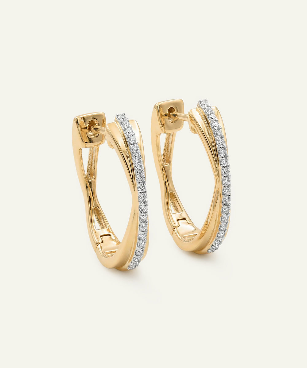 Gold hoop earrings with diamond accents on a light beige background
