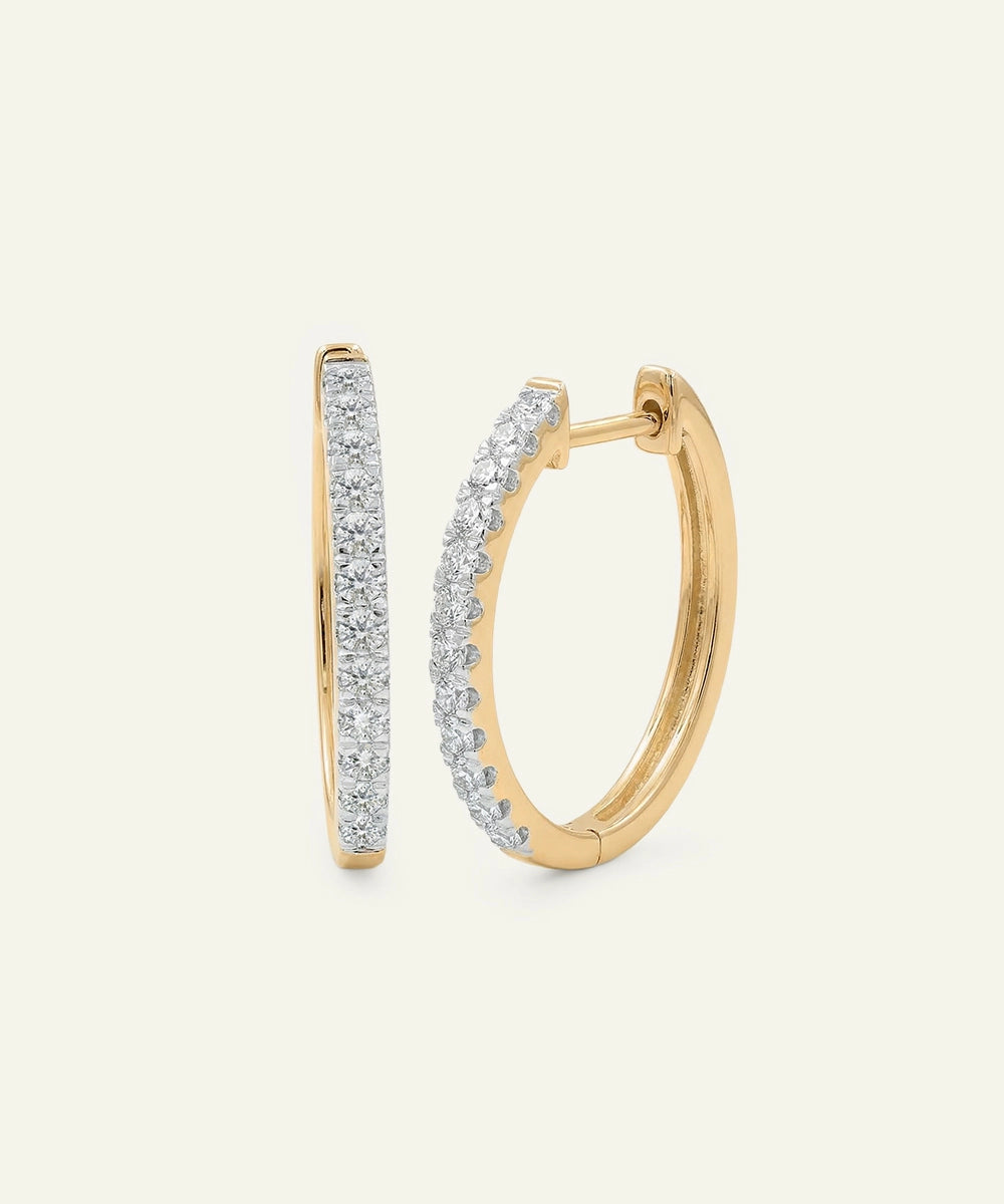 Gold hoop earrings with diamond accents on a light beige background