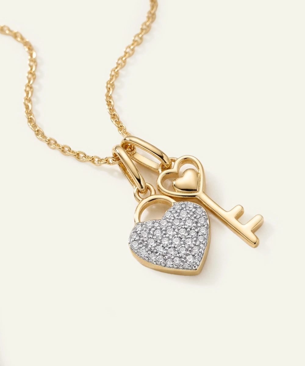 Gold necklace with heart padlock and key pendant on a light beige background