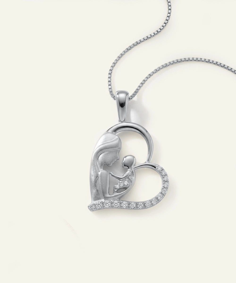 Silver heart-shaped pendant with a mother and child design on a white background