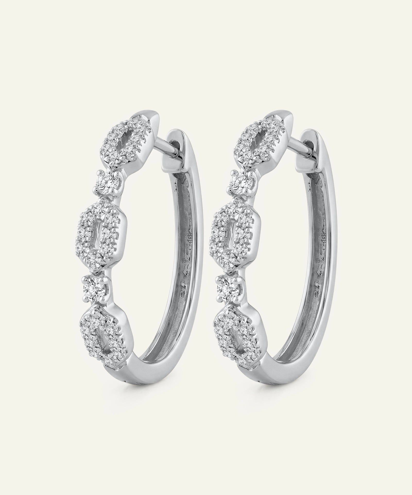 Pair of silver hoop earrings with clear gemstones on a white background