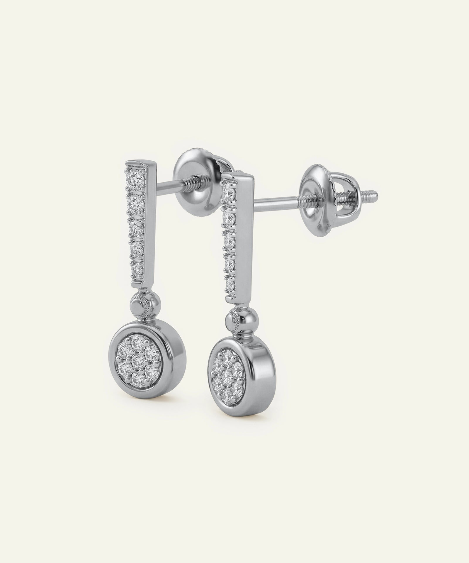 Silver earrings with circular designs and small diamonds on a light gray background