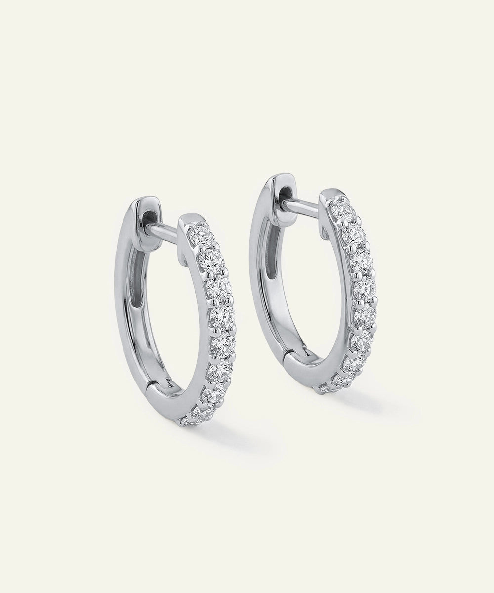 Pair of silver hoop earrings with embedded stones on a light gray background