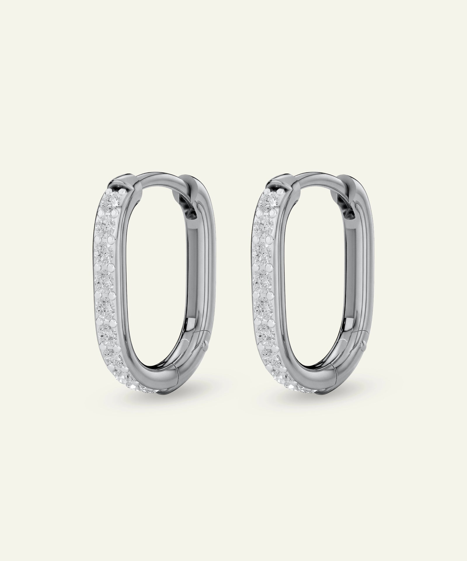 Pair of silver hoop earrings with clear gemstones on a light gray background