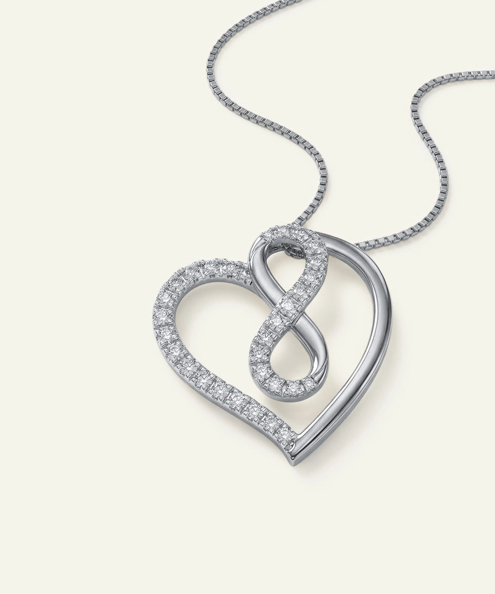 Silver heart-shaped pendant with an infinity symbol on a light gray background