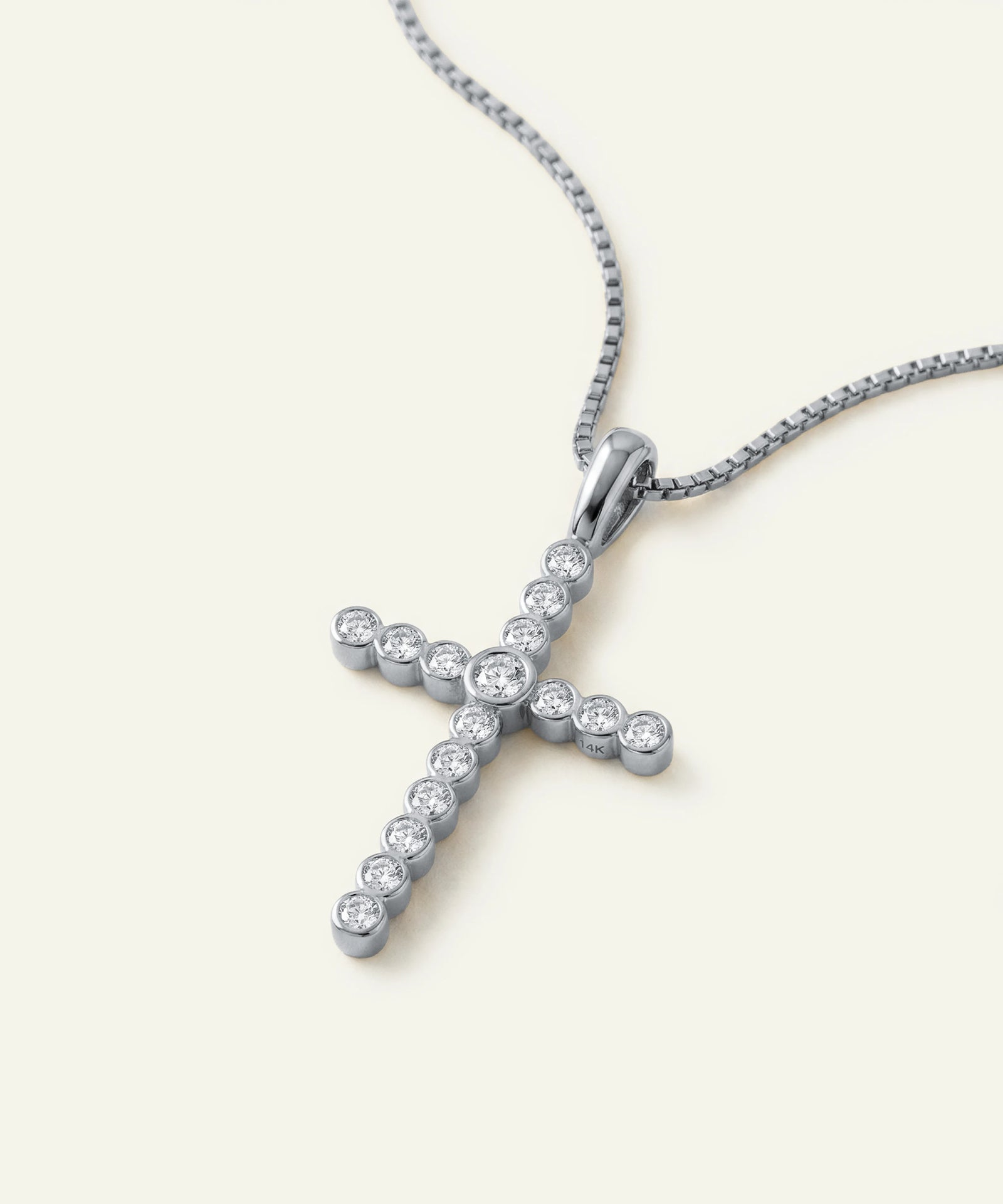 Silver cross pendant with diamonds on a white background