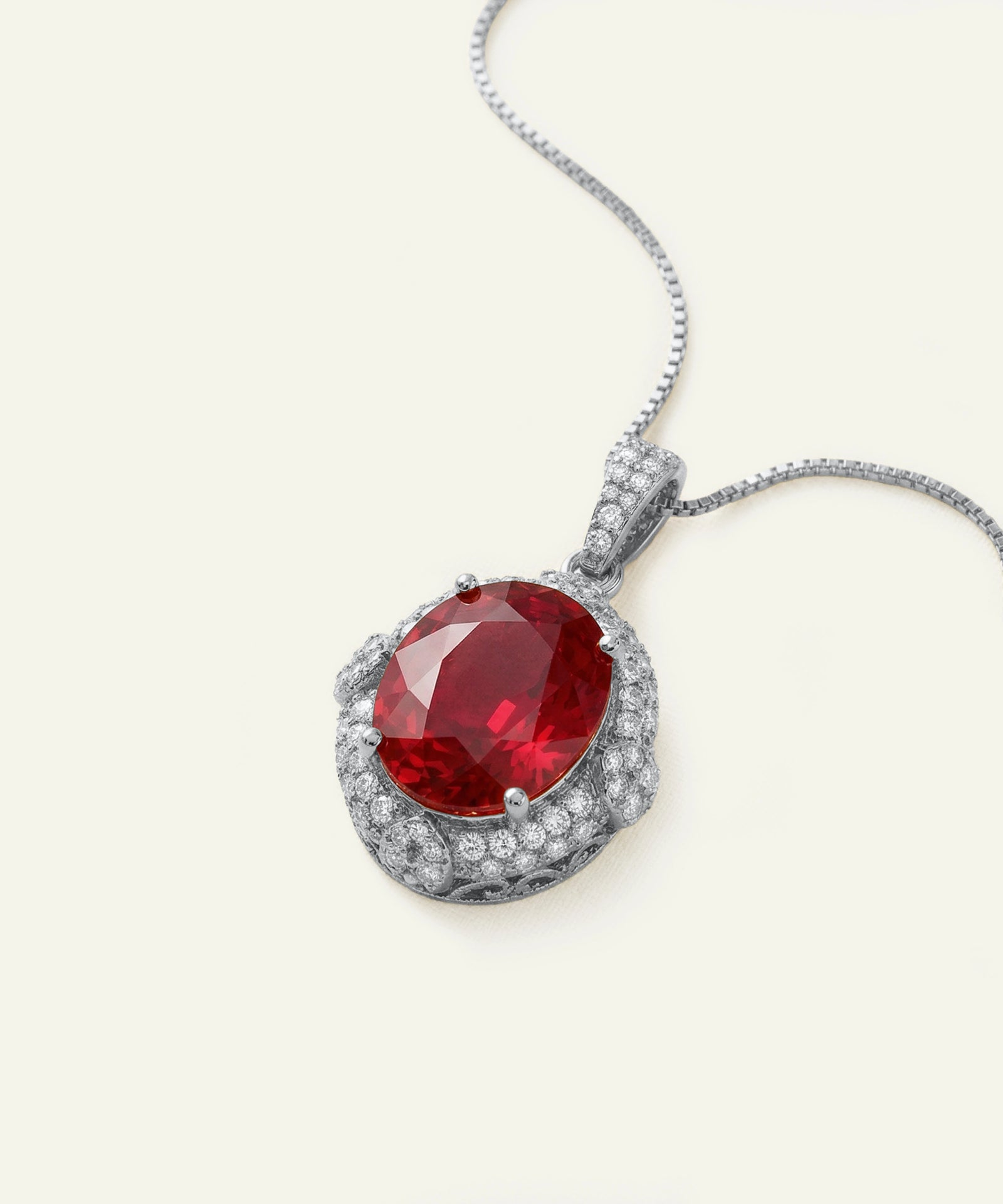 Silver pendant with a red gemstone on a white background