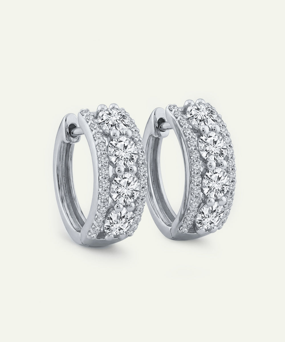 Pair of silver hoop earrings with clear gemstones on a light gray background