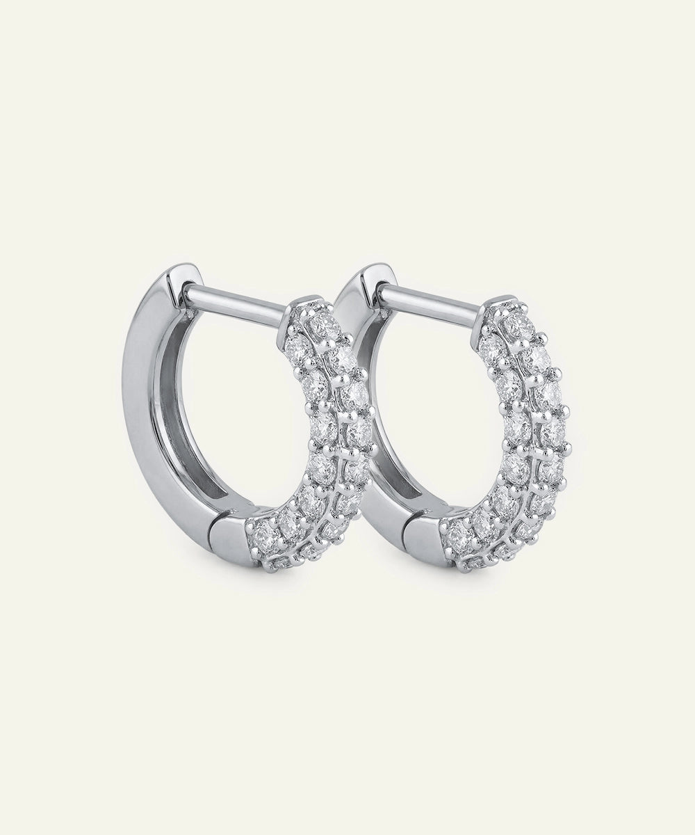 Pair of silver hoop earrings with clear gemstones on a light gray background
