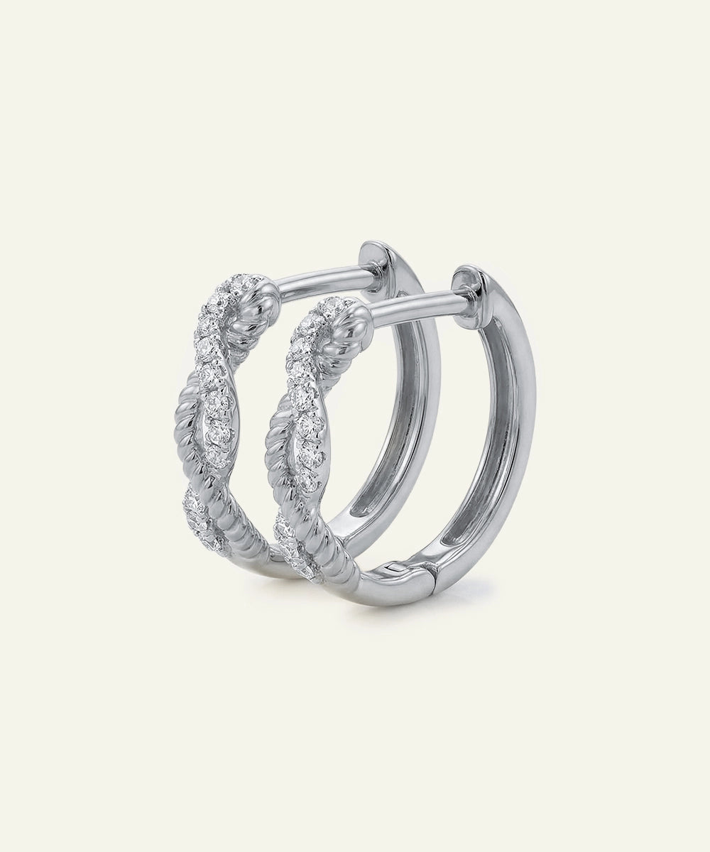 Silver hoop earrings with intricate design on a light gray background