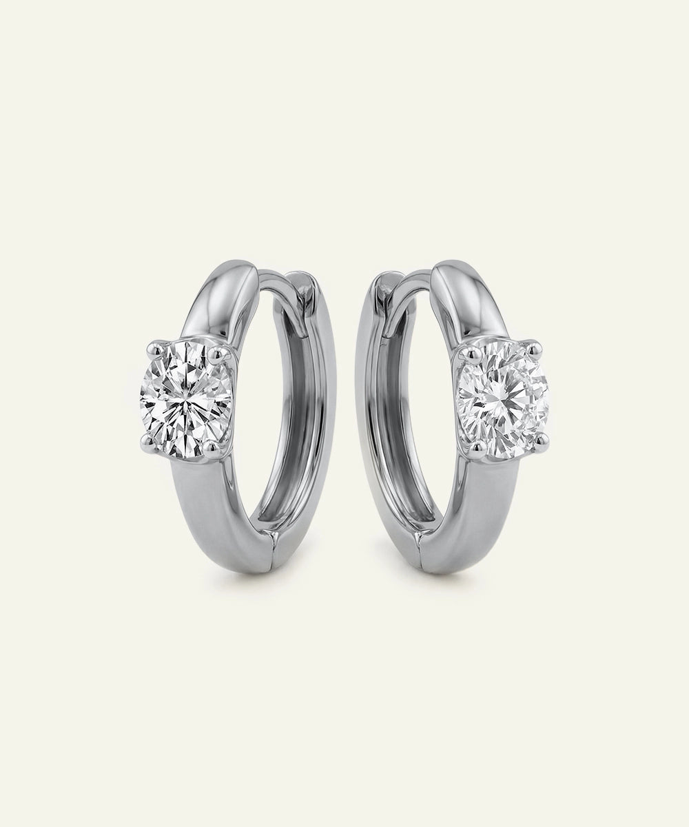 Pair of silver hoop earrings with clear gemstones on a white background