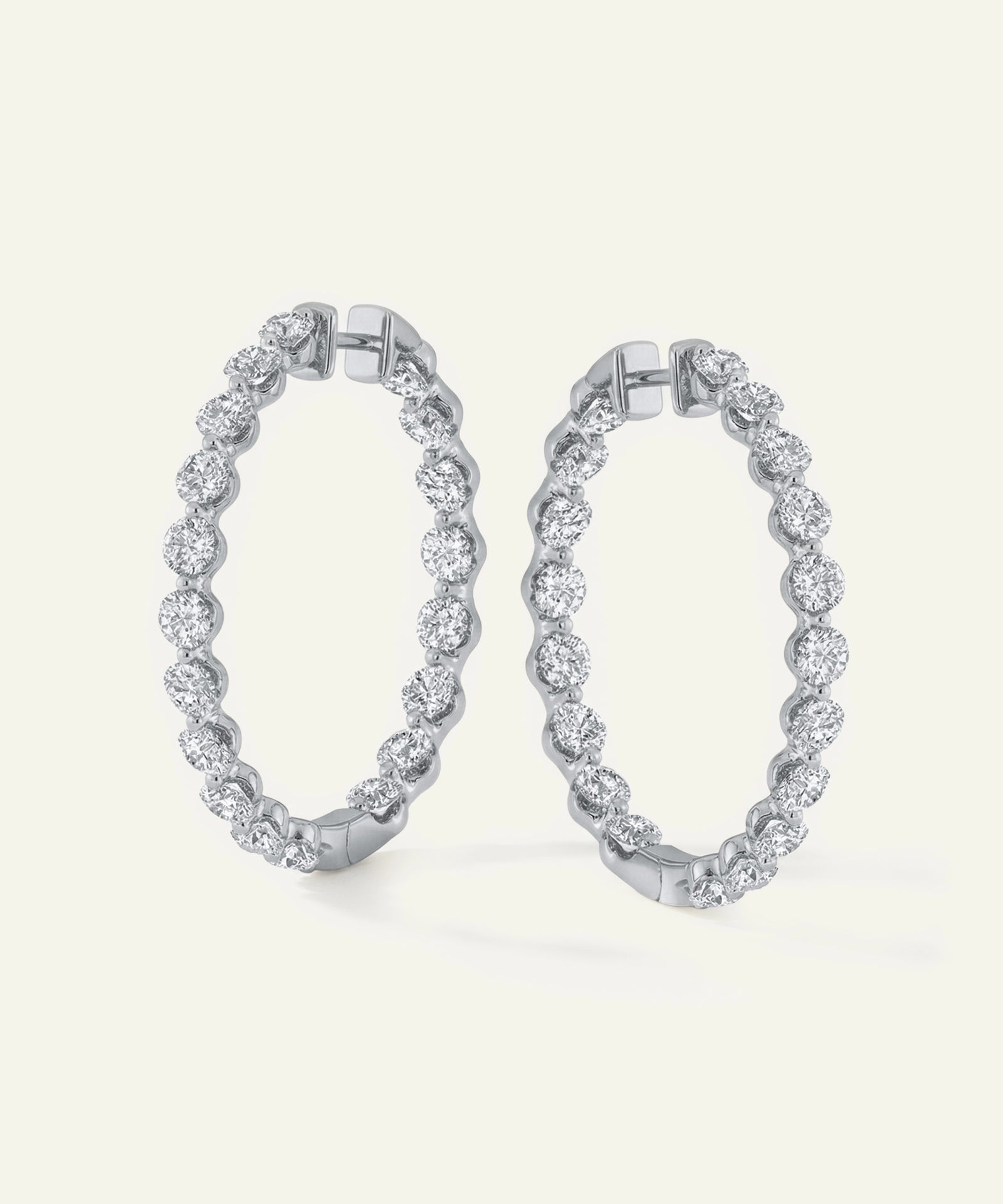 Pair of silver hoop earrings with clear gemstones on a white background