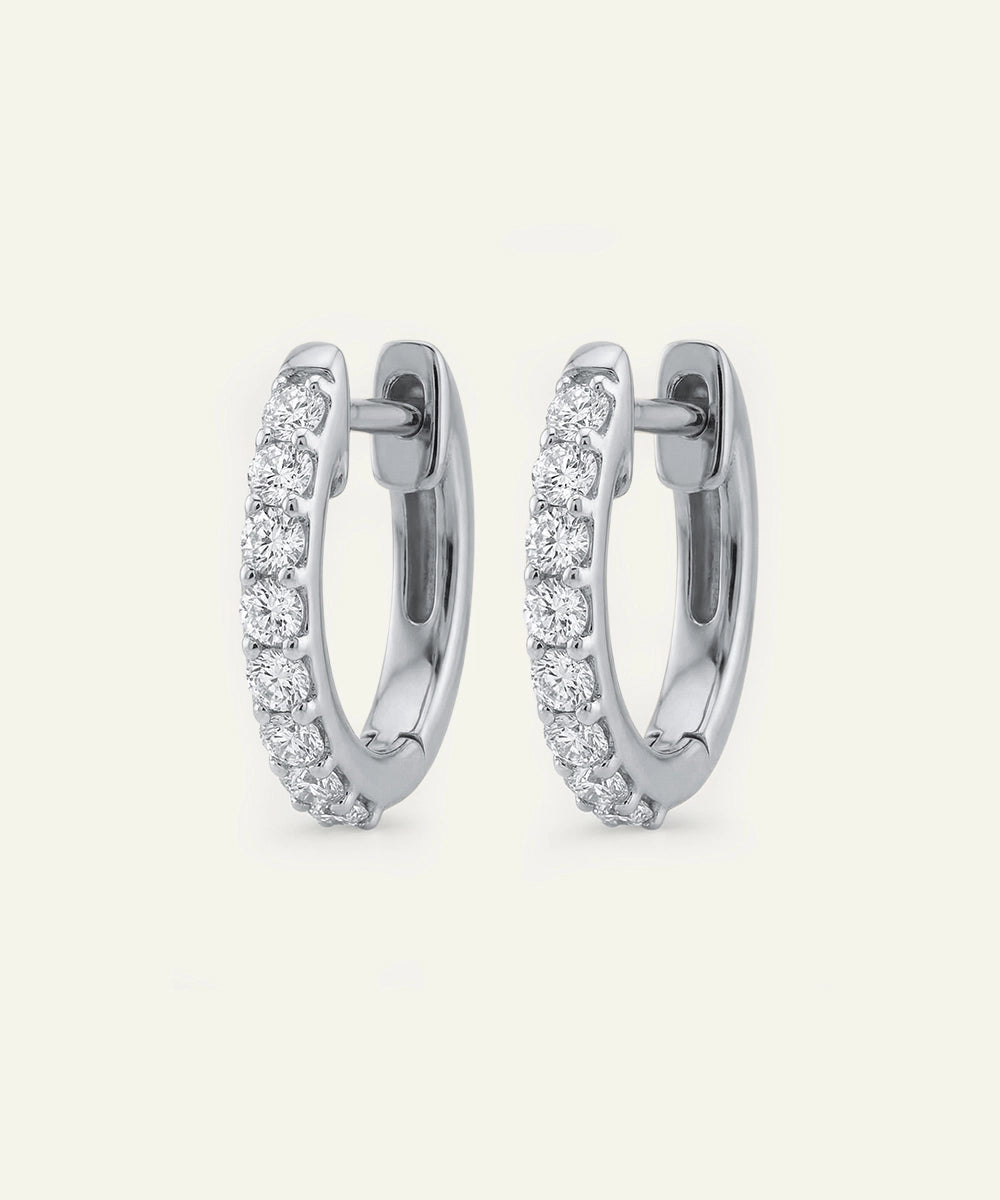Pair of silver hoop earrings with clear gemstones on a white background