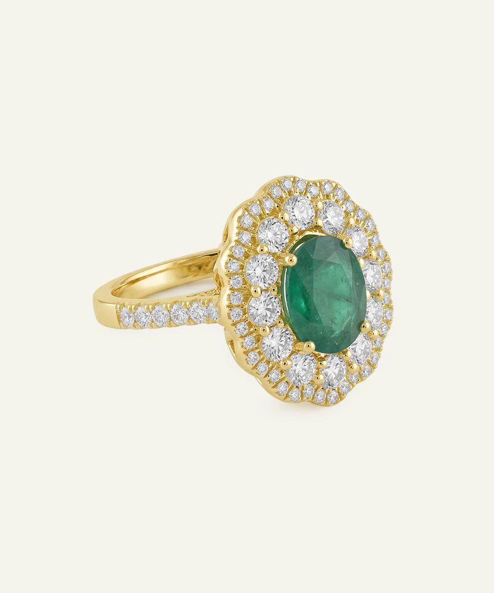 Gold ring with a green gemstone and diamond accents on a beige background