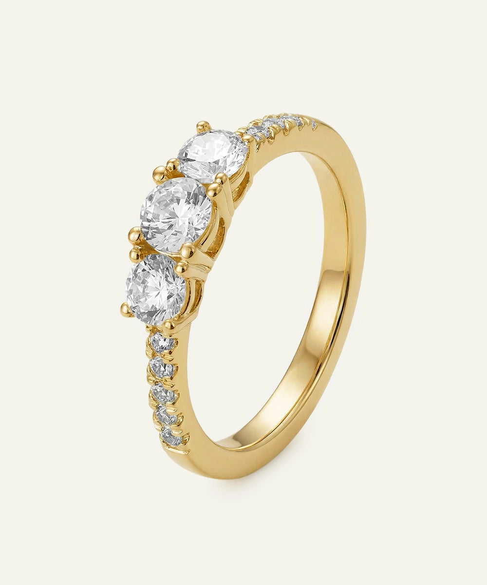 Gold ring with clear gemstones on a light beige background