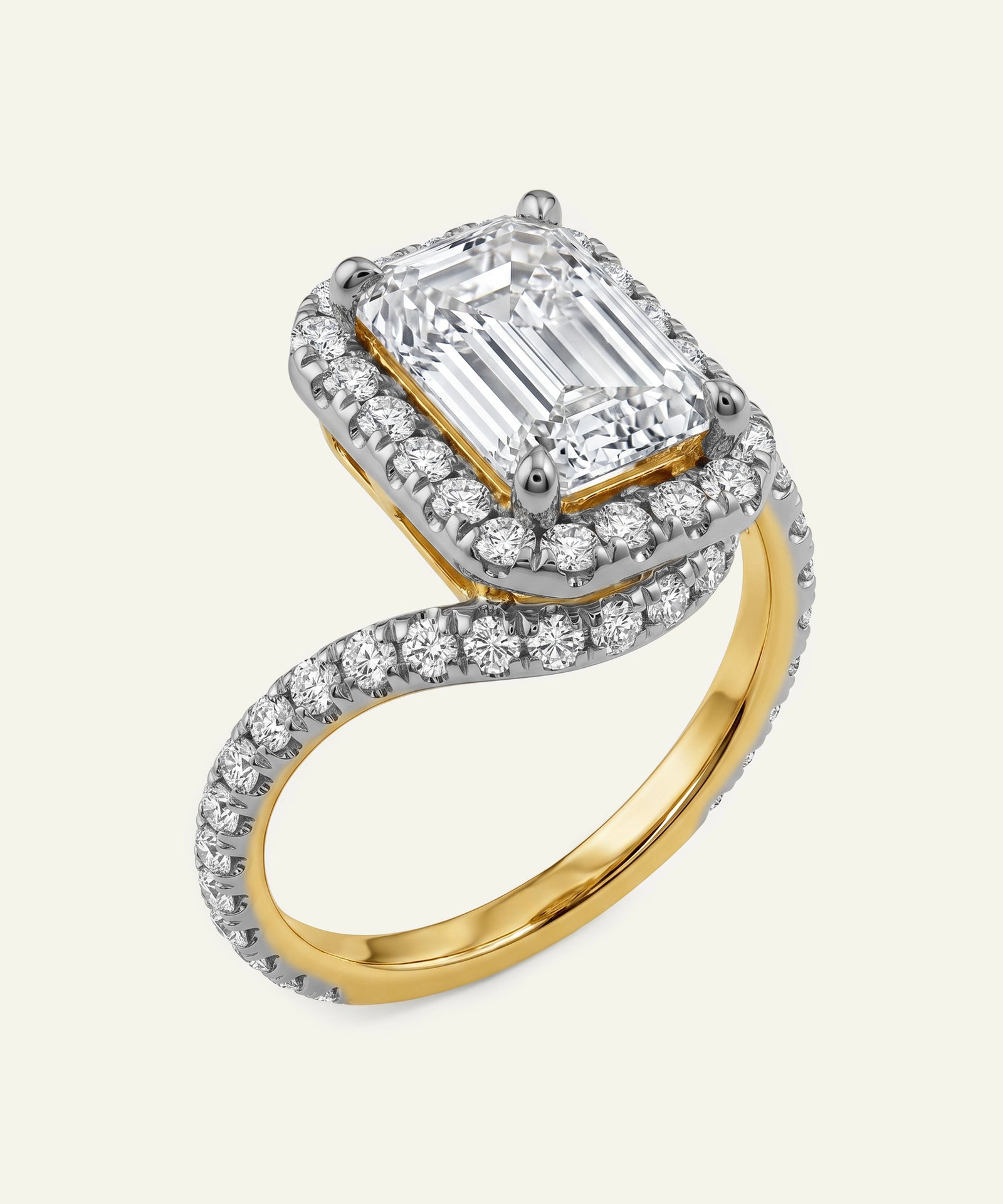 Two-tone diamond ring with emerald-cut center stone on a white background