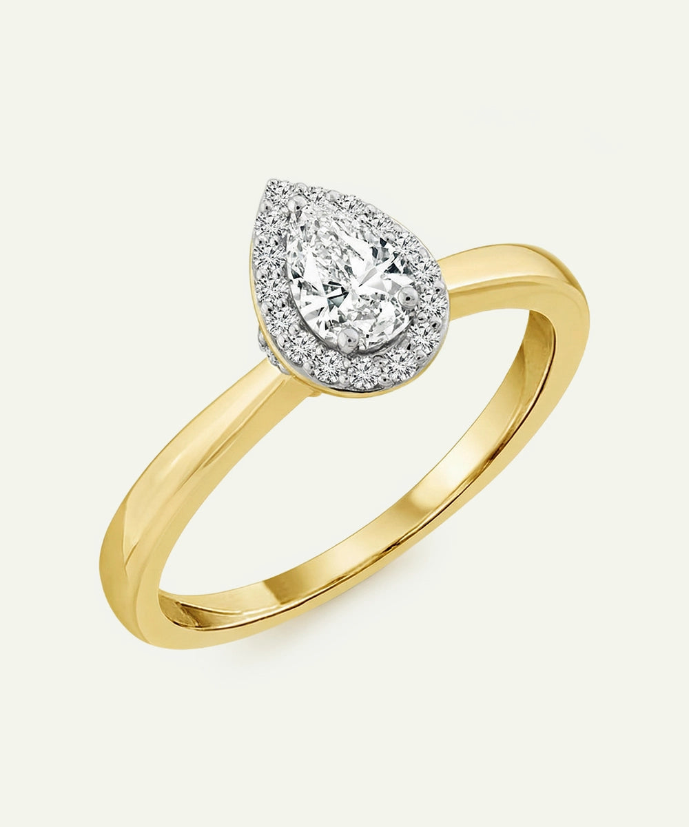 Gold ring with a pear-shaped diamond on a white background