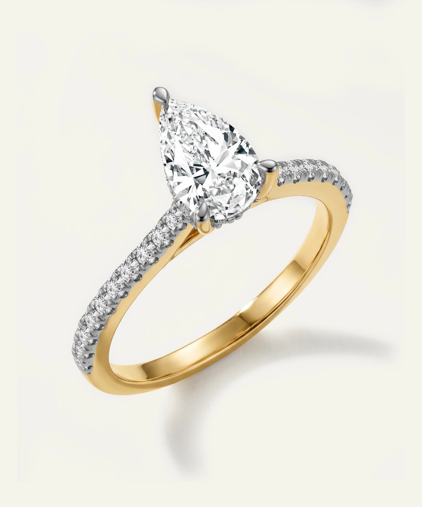 Gold ring with a pear-shaped diamond on a light gray background