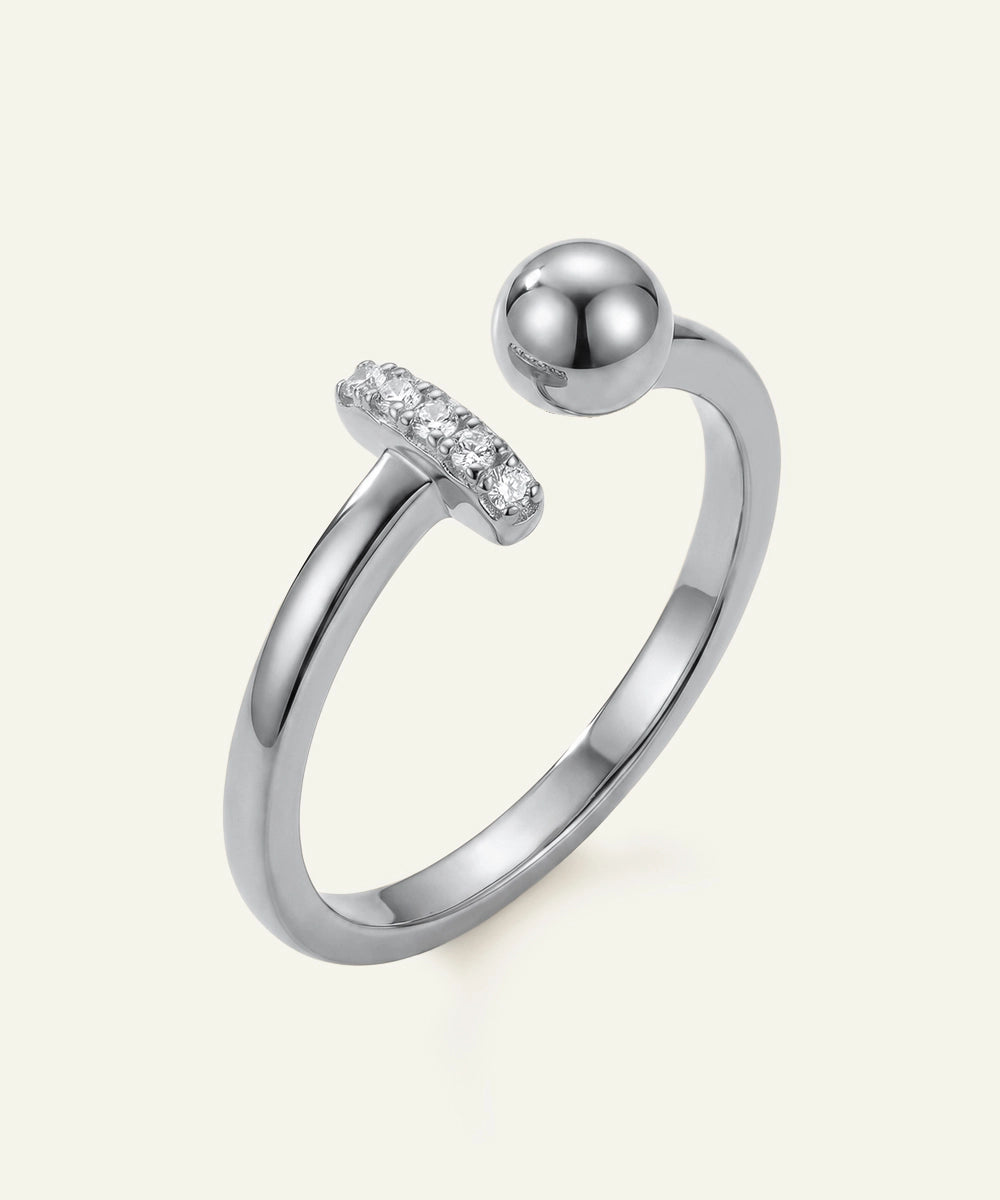 Silver ring with a spherical design and small diamonds on a light gray background