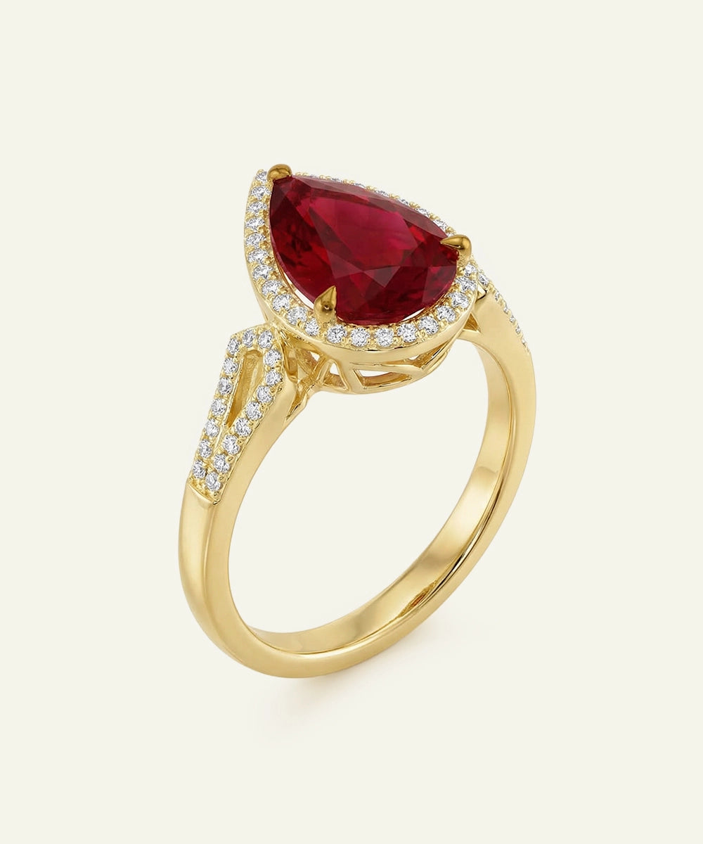 Gold ring with a red gemstone and diamond accents on a white background