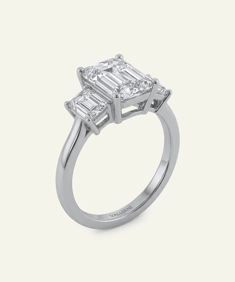 Diamond ring with two emerald-cut diamonds on a light gray background