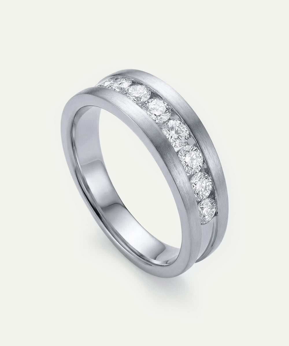 Silver ring with embedded diamonds on a light gray background