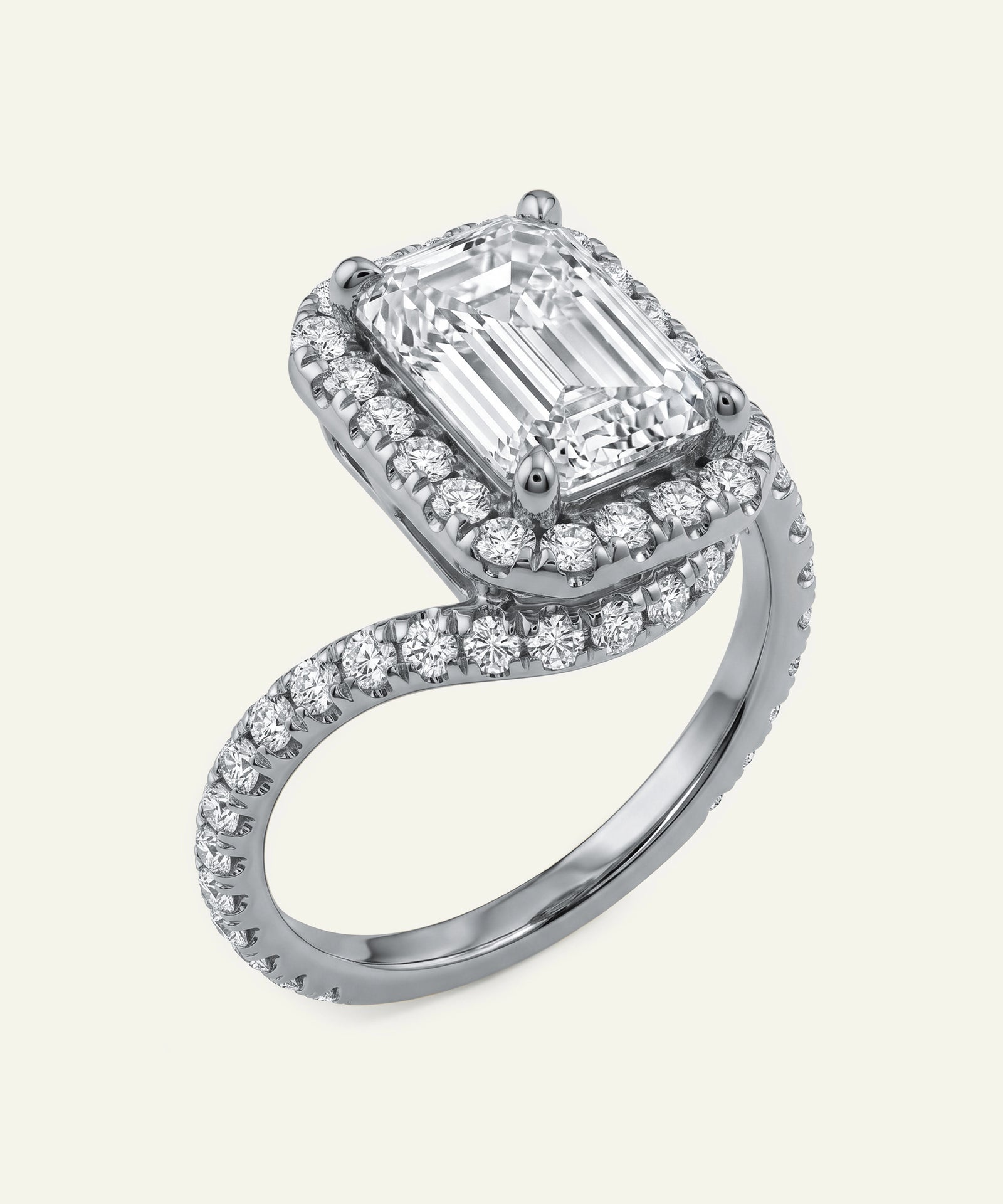Diamond ring with emerald-cut center stone and halo on a white background