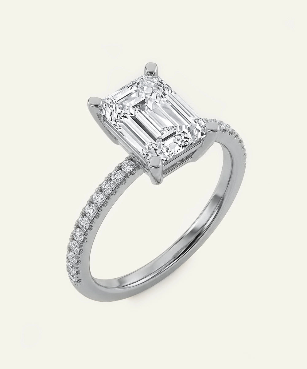 Diamond ring with a prominent emerald-cut center stone on a white background