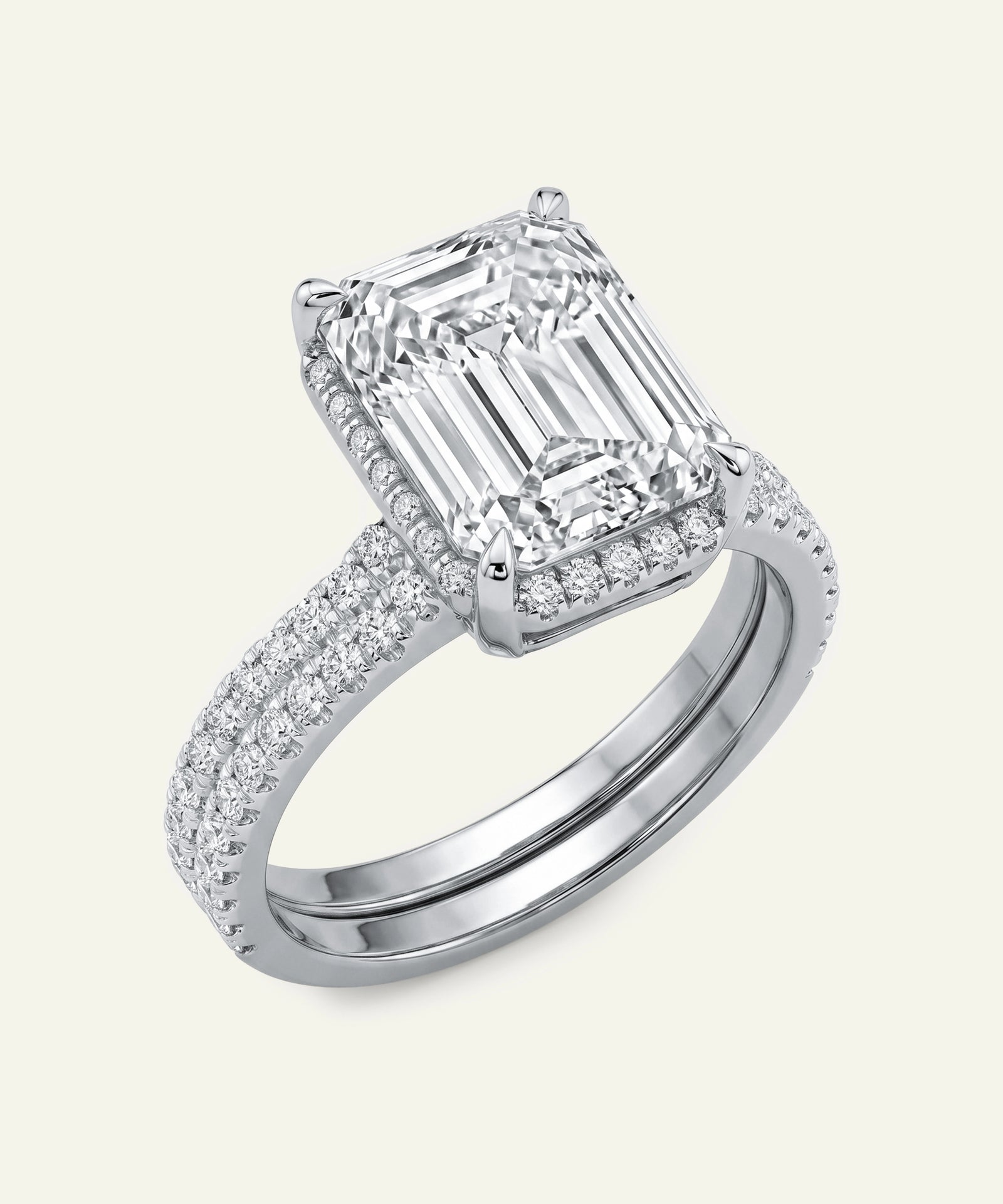 Diamond ring with emerald-cut center stone on a white background