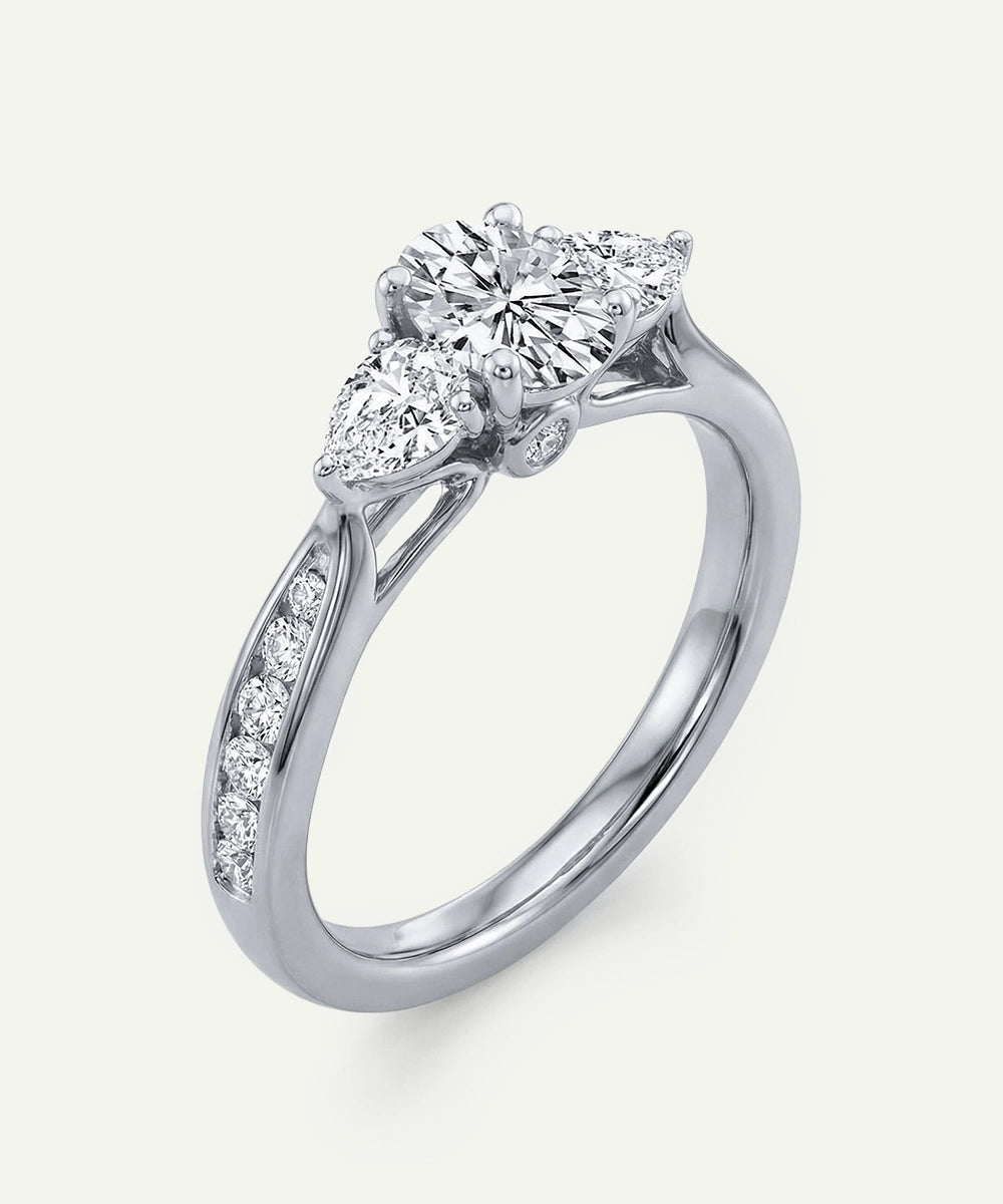 Diamond ring with pear-shaped and round diamonds on a white background
