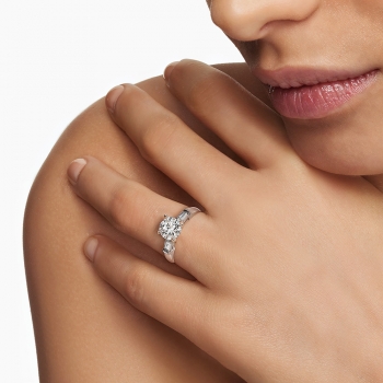 A woman touching her chin, wearing a diamond ring.