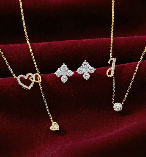 Gold diamond heart necklaces, floral diamond stud earrings, initial “J” pendant, and solitaire diamond necklace displayed on red velvet
